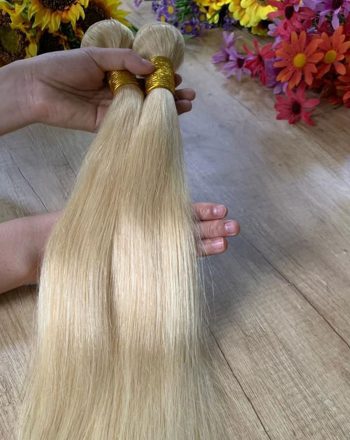 A person holding two pieces of hair on top of a table.